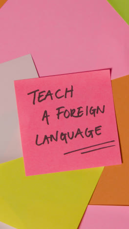 Vertical-Video-Education-Concept-Of-Revolving-Sticky-Notes-With-Teach-A-Foreign-Language-Written-On-Top-Note